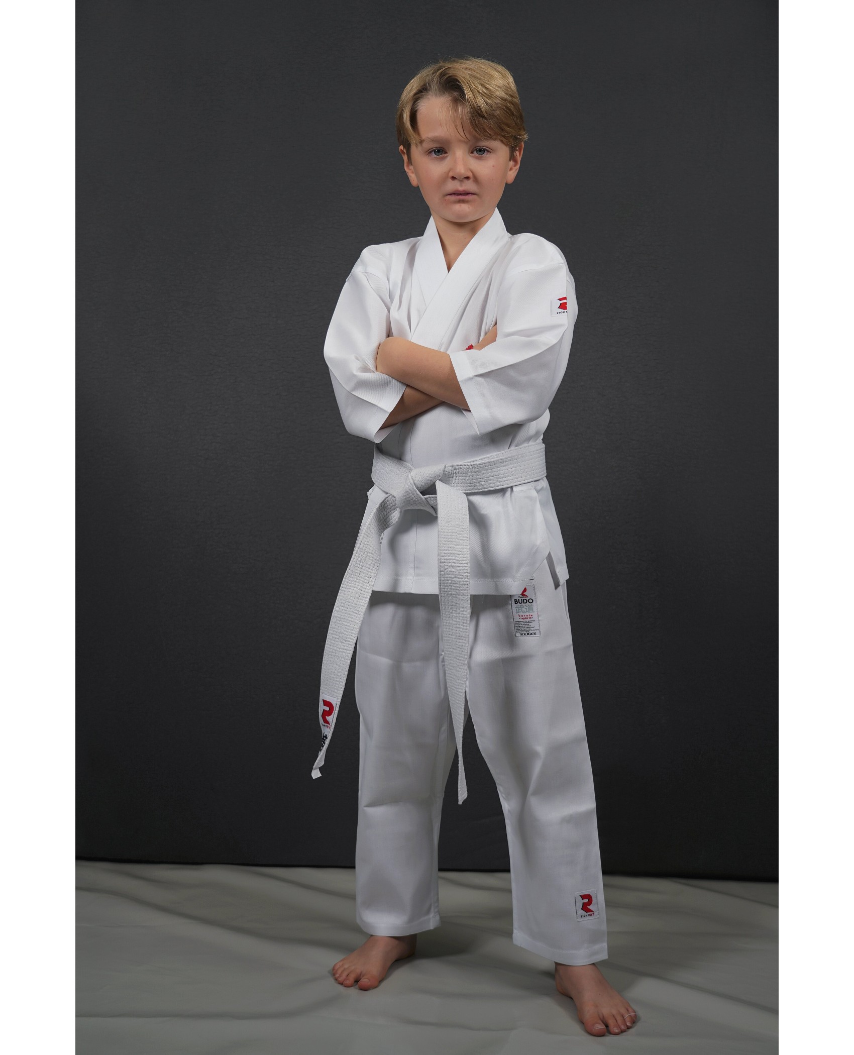 Petite Fille Dans Le Karaté Costume Kimono En Studio À Fond Noir. Enfant  Femme Montre Judo Ou Karaté Stans En Uniforme Blanc Avec Ceinture Jaune.  Art Martial Sport Individuel Pour Les Enfants.